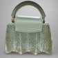 Light green handbag with metallic handle on a gray background