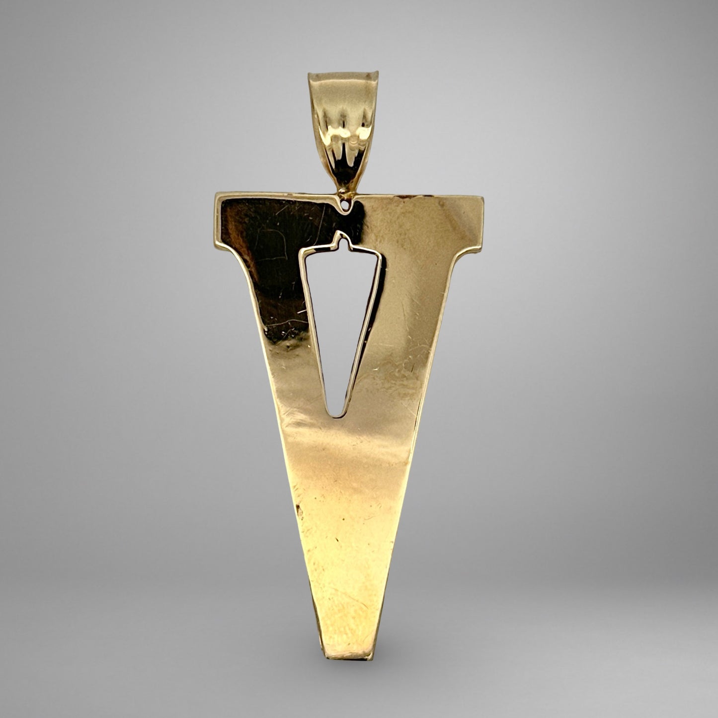 Gold pendant shaped like the letter 'V' on a gray background