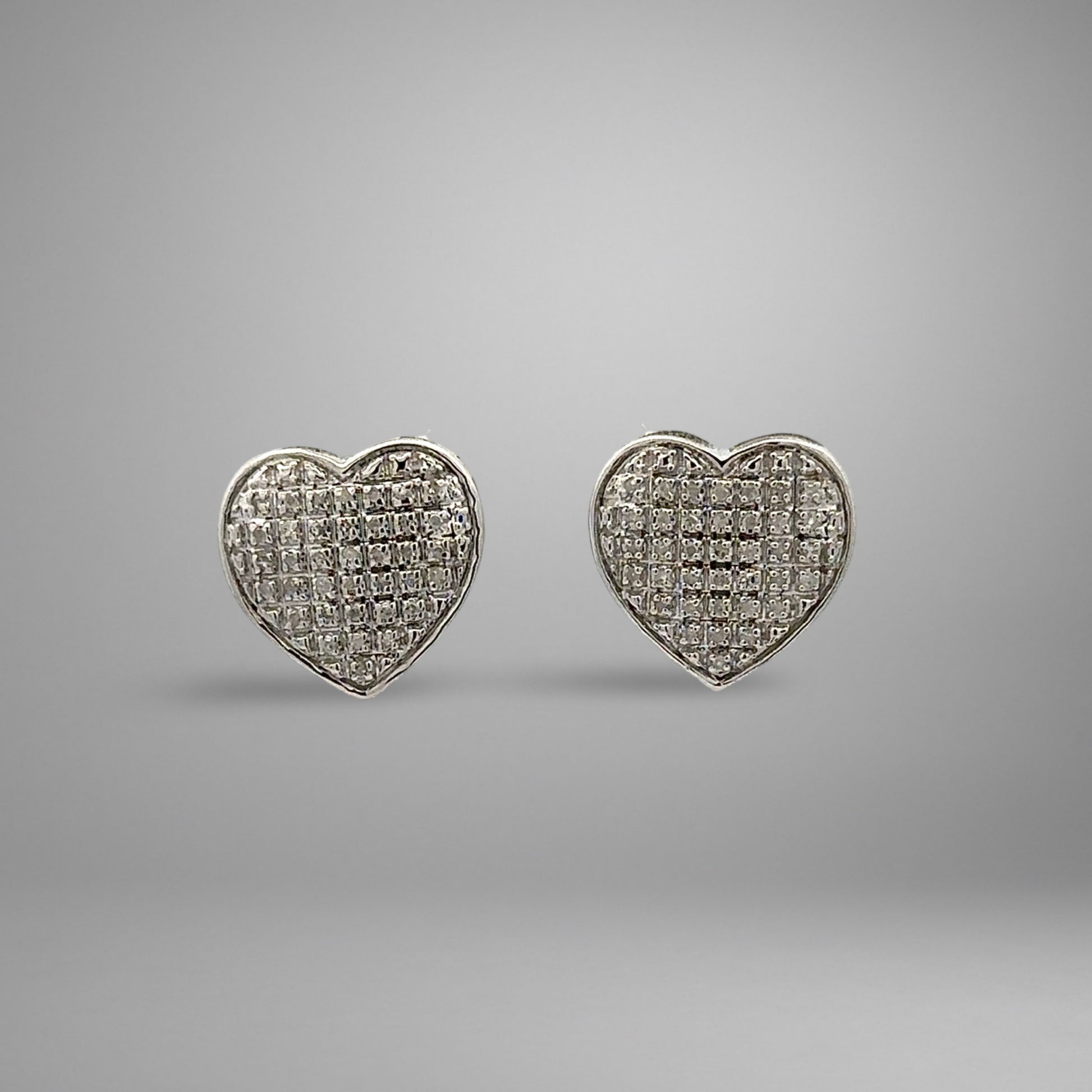 Heart-shaped white gold earrings on a gray background
