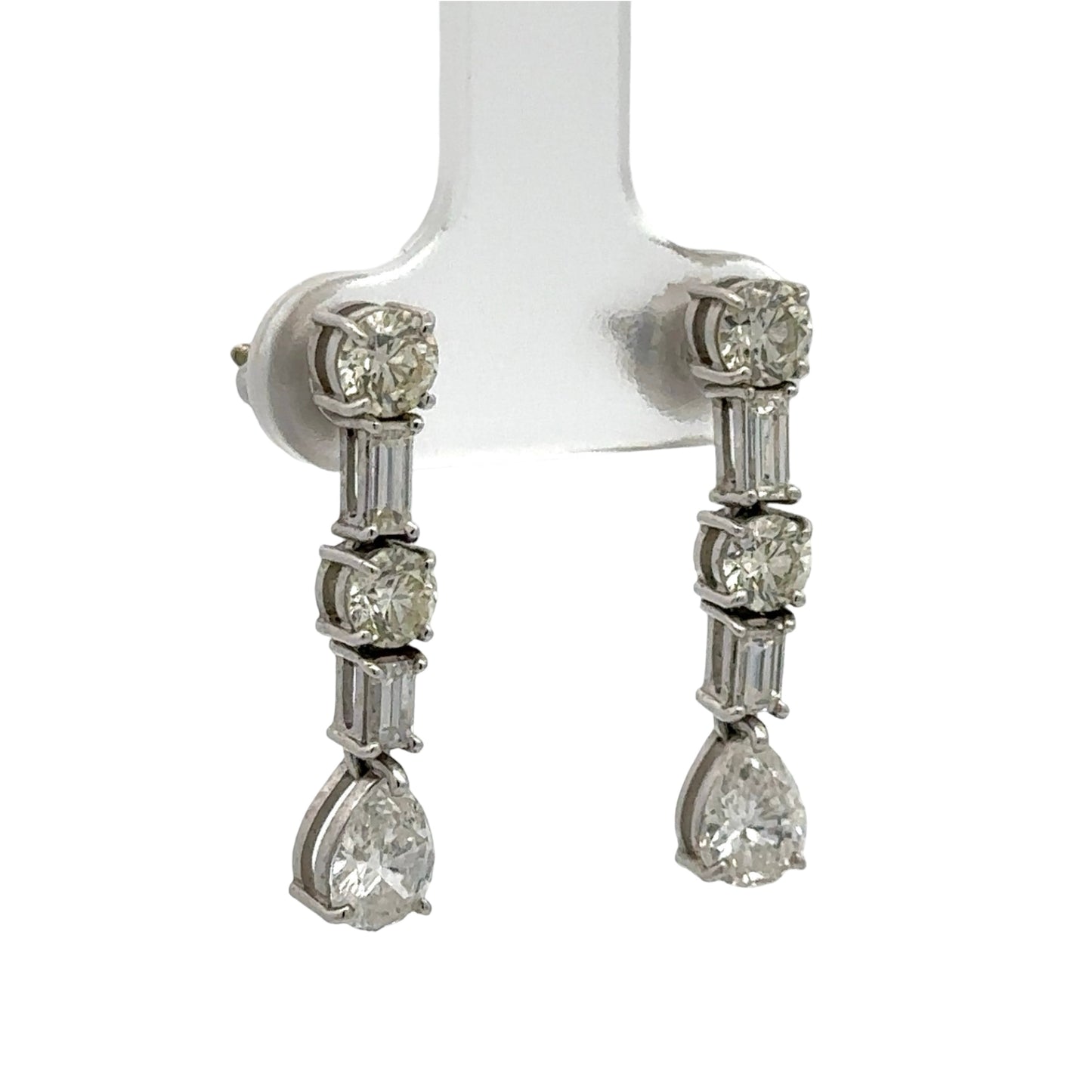 Diamond earrings on a white stand against a white background