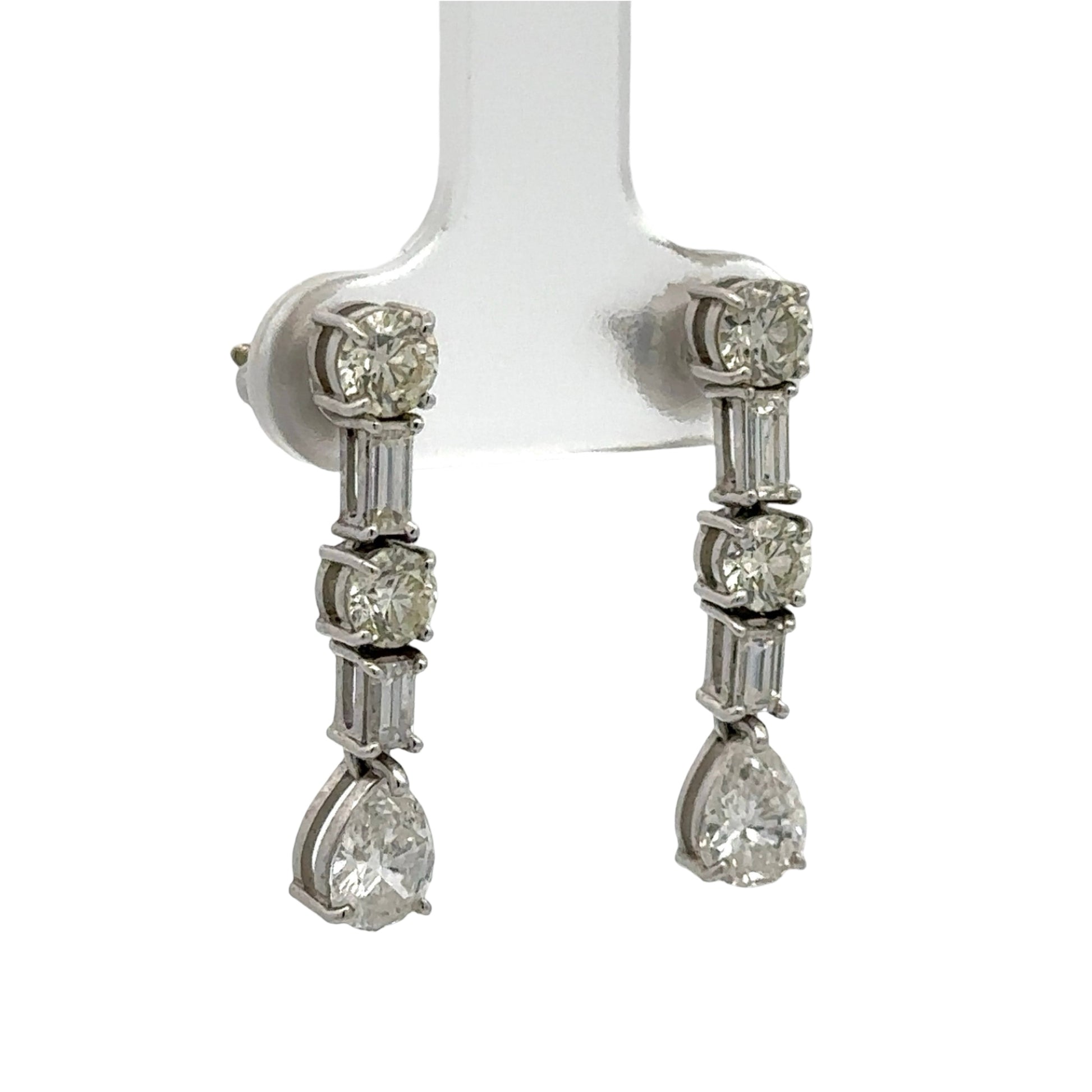 Diamond earrings on a white stand against a white background