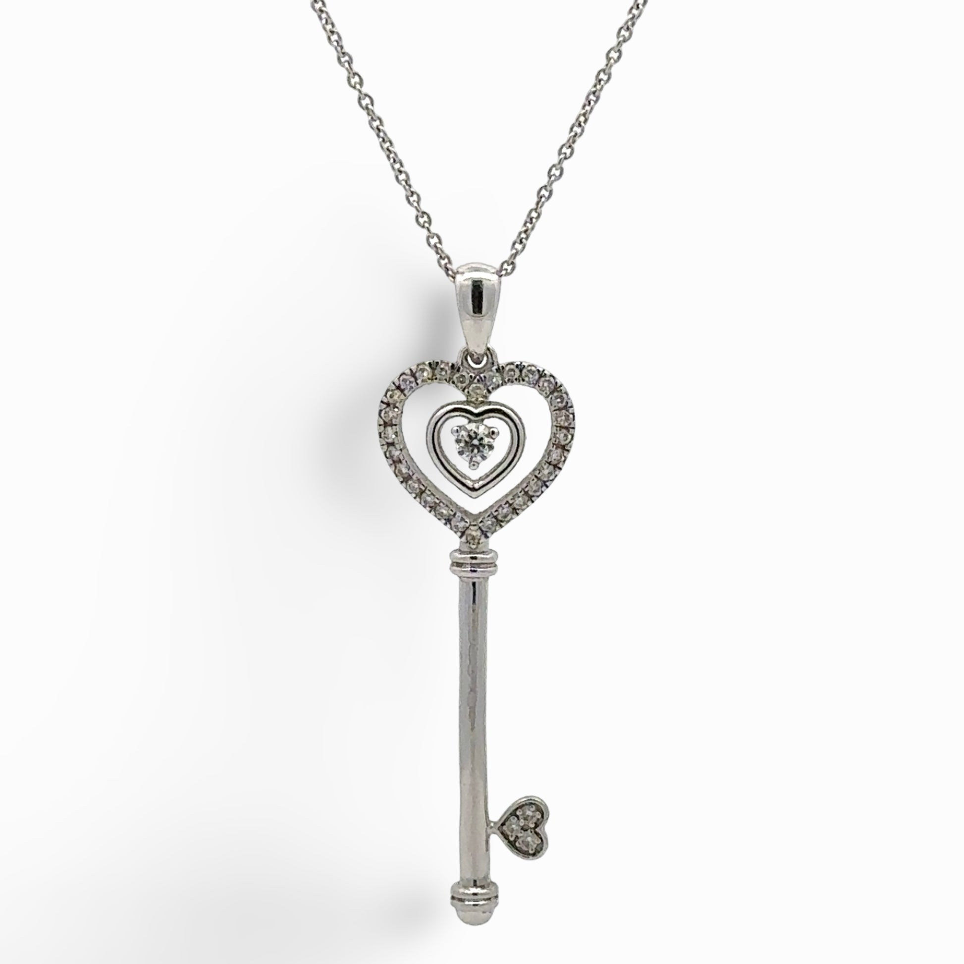 white gold key shaped pendant on a thin chain with attached hearts
