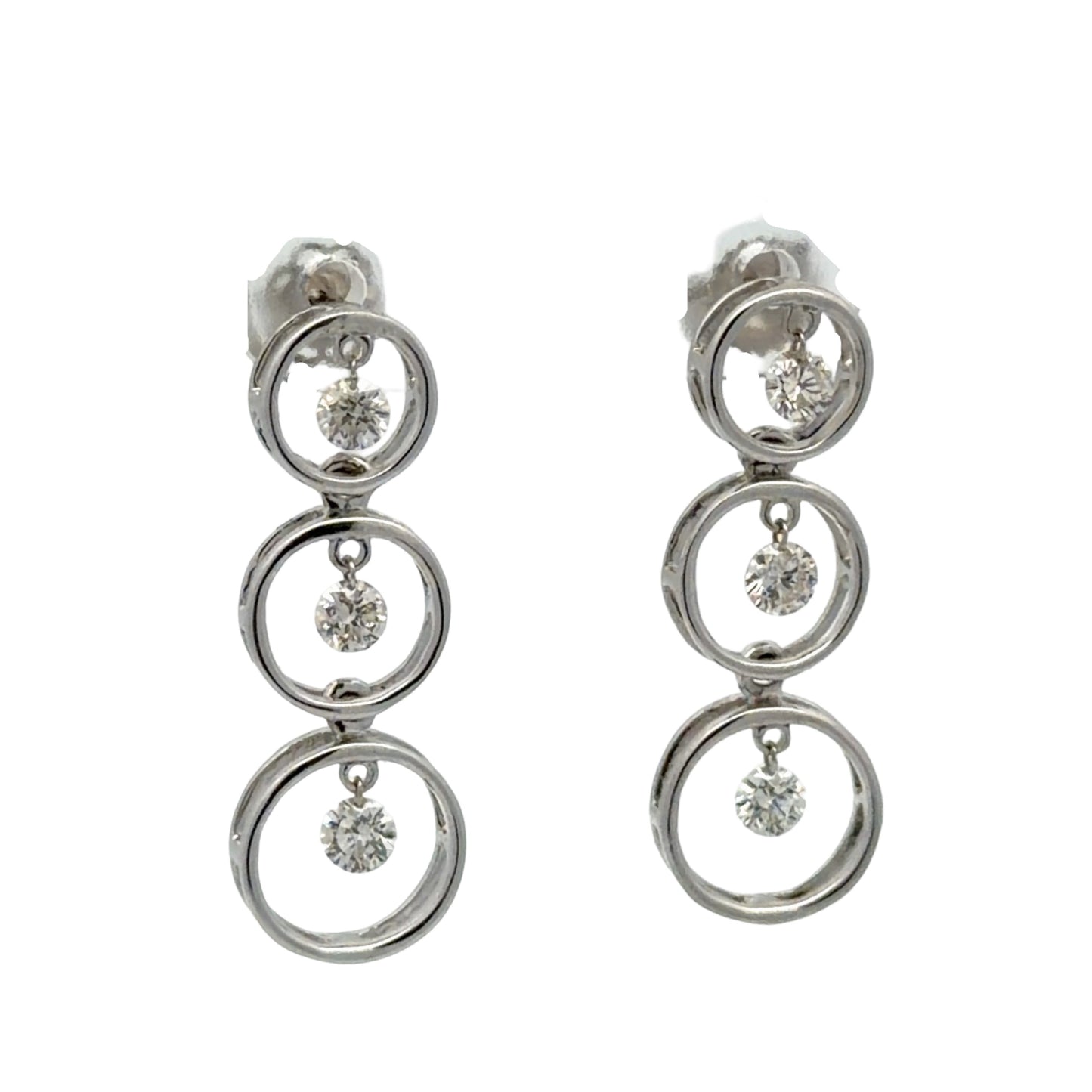 Pair of white gold earrings with multiple circular designs on a white background with floating diamonds in each circle