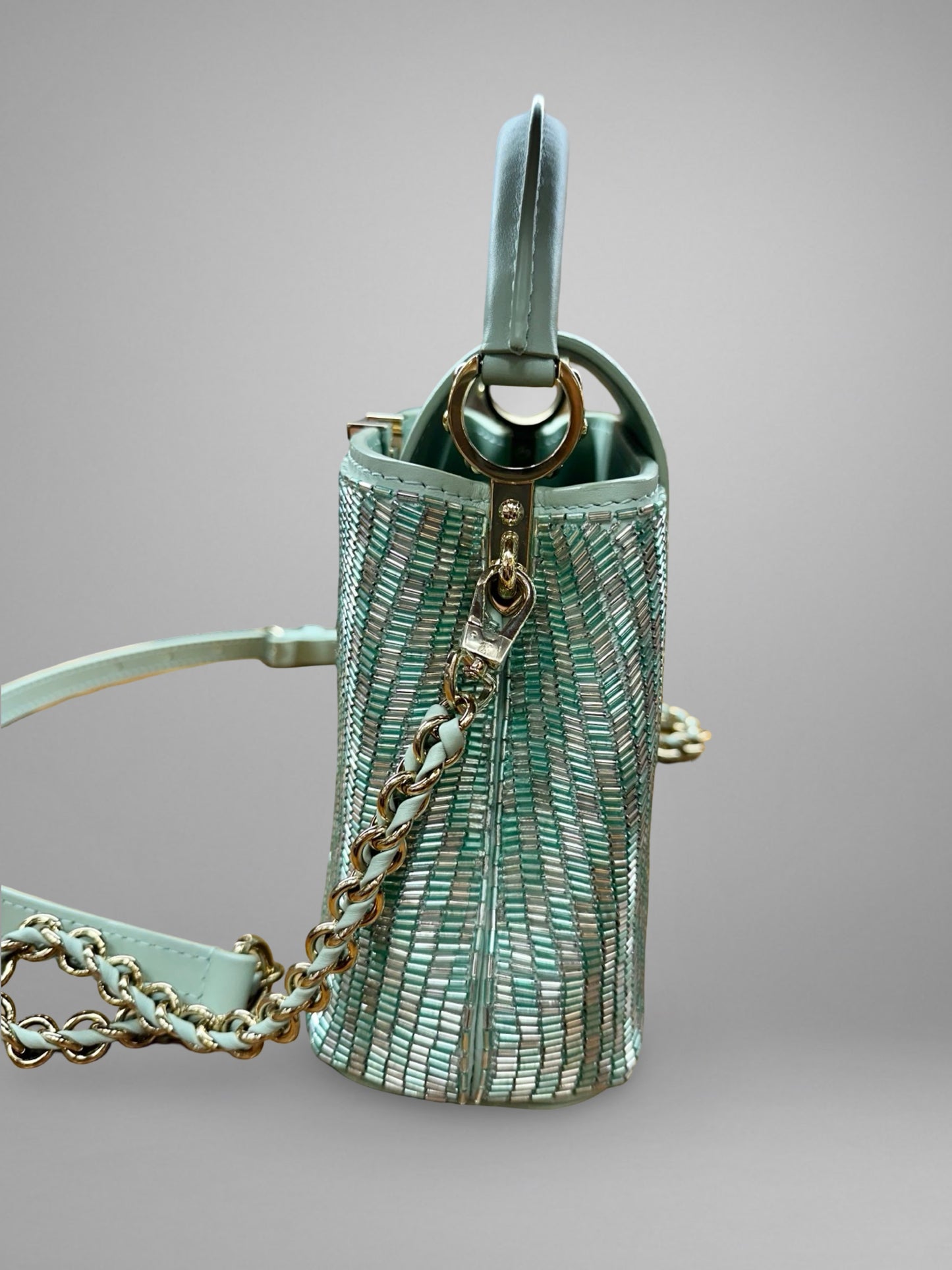 Light blue handbag with chain detail on a gray background