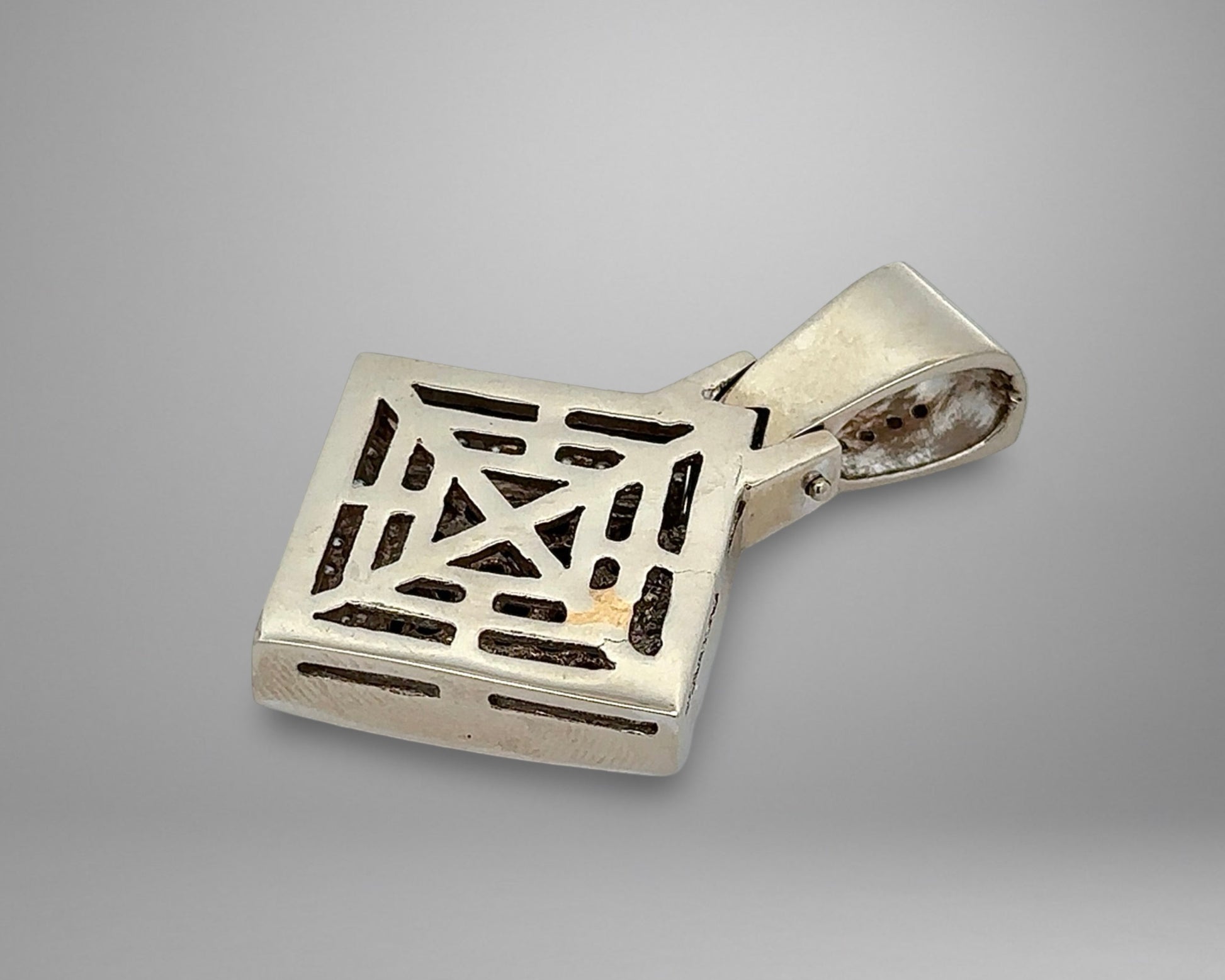 White gold pendant with geometric design on a gray background