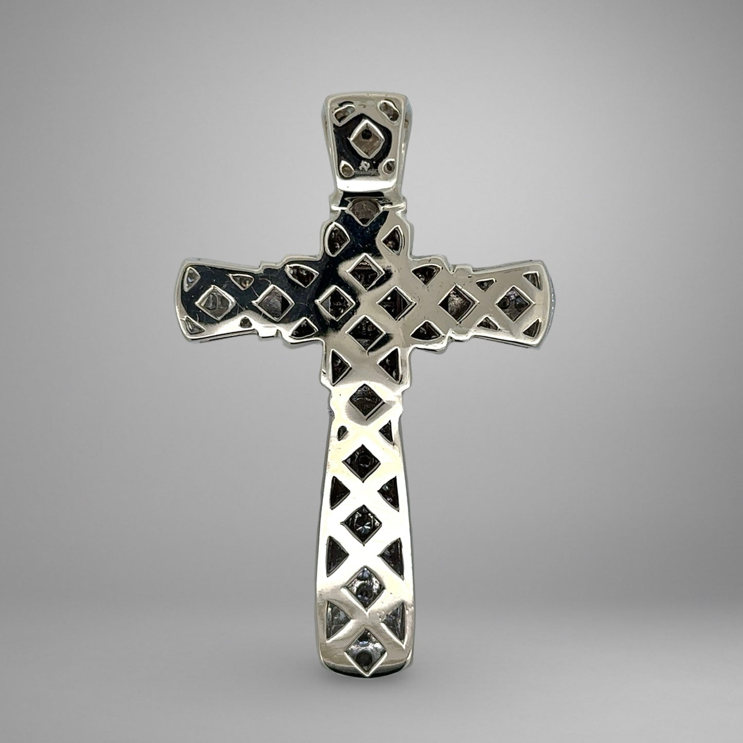 White gold cross pendant with intricate designs on a gray background