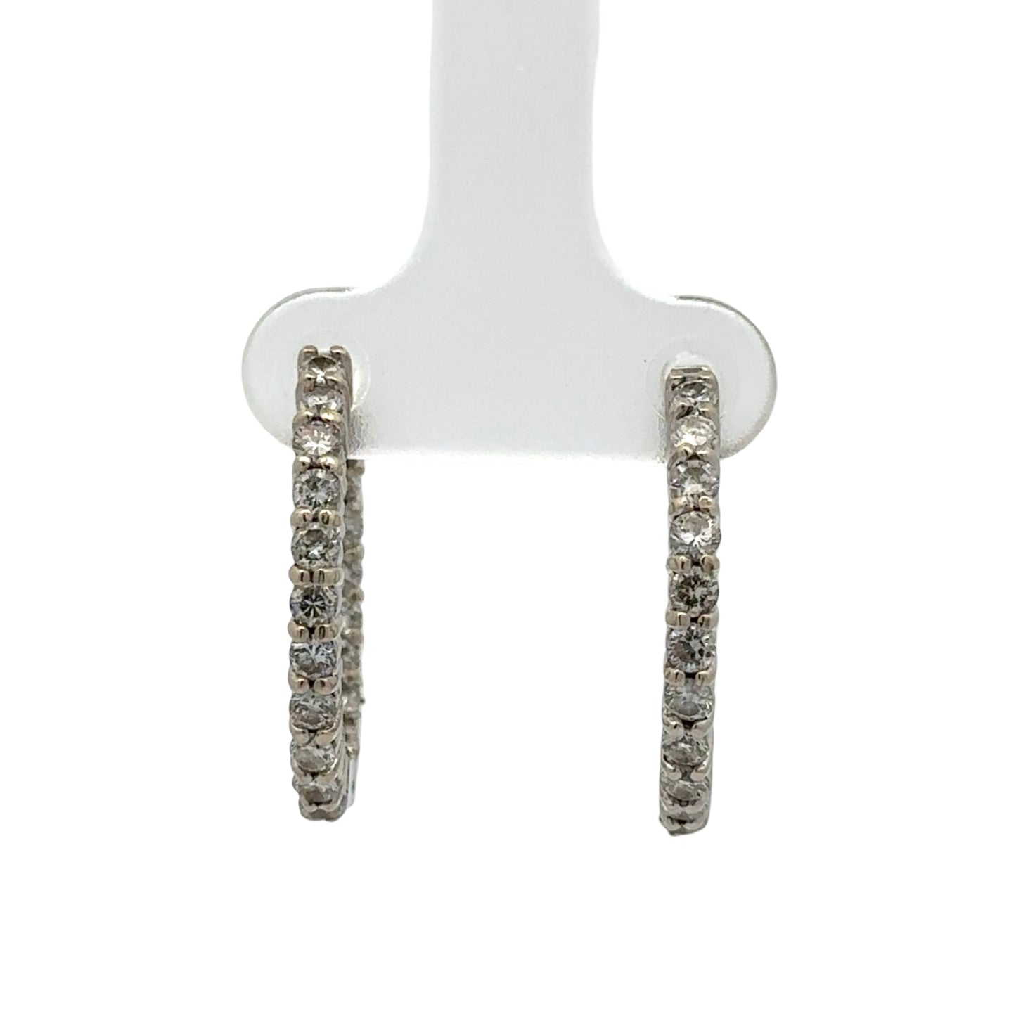 Pair of diamond hoop earrings on a white stand against a white background