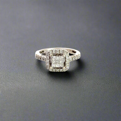Front of ring with 9 princess-cut diamonds in center surrounded by small round diamonds on half of sides and around princess-cuts.