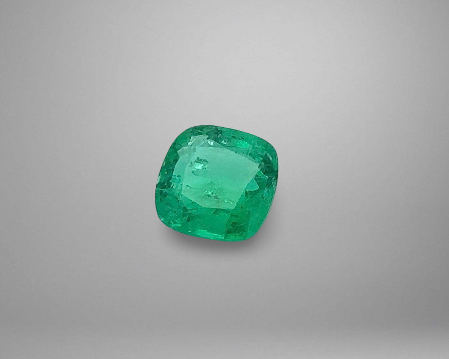 Cushion-shaped emerald on a gray background
