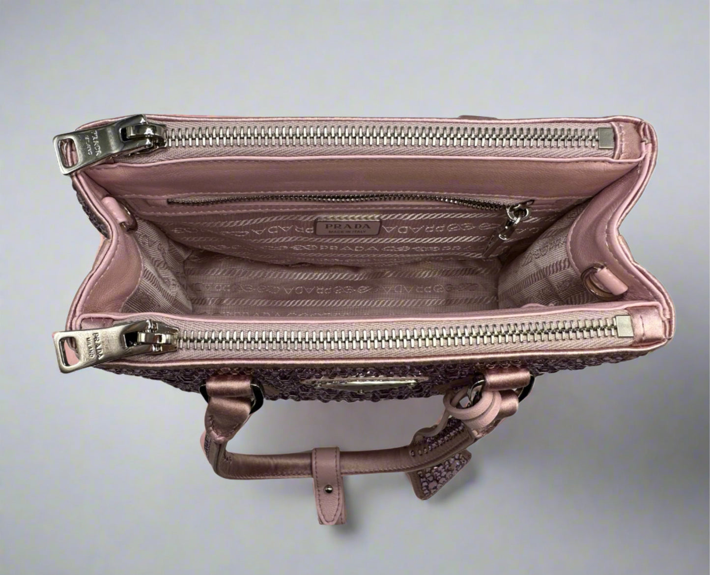 Pictured: The inside of the Prada Galleria Crystal mini satin bag in pink with the pocket zippers closed. There are 2 zipper pockets on the top of the bag on each side. There is a zipper pocket on the inside of the bag. No imperfections.