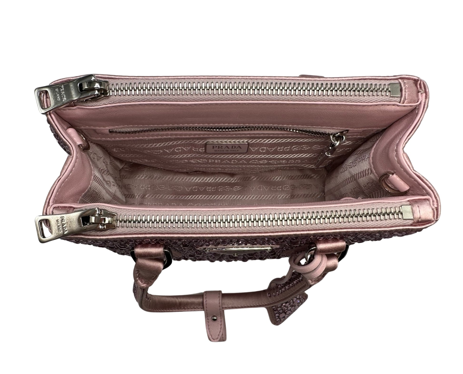 Pictured: The inside of the Prada Galleria Crystal mini satin bag in pink with the pocket zippers closed. There are 2 zipper pockets on the top of the bag on each side. There is a zipper pocket on the inside of the bag. No imperfections.