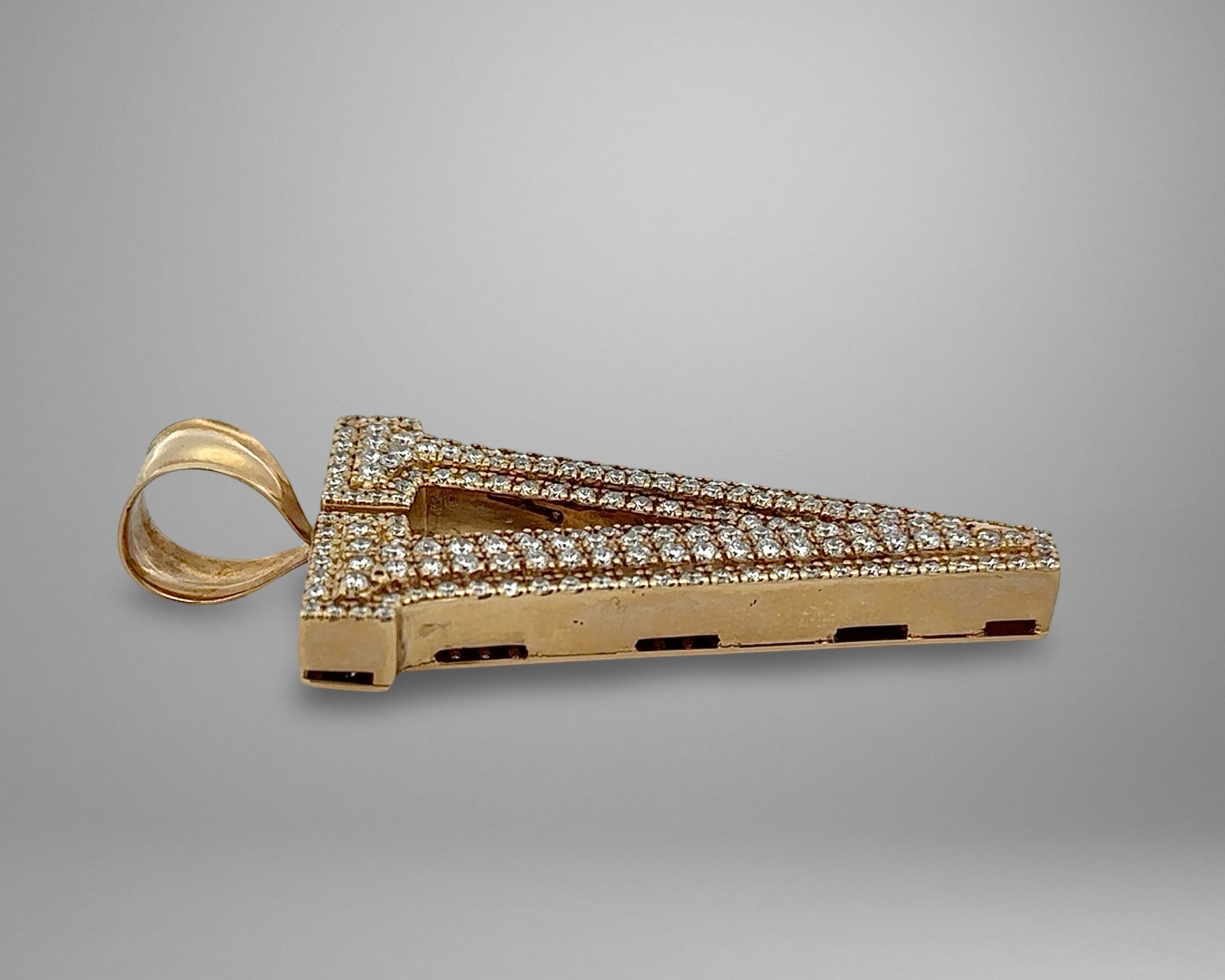 Gold pendant with diamond accents on a gray background