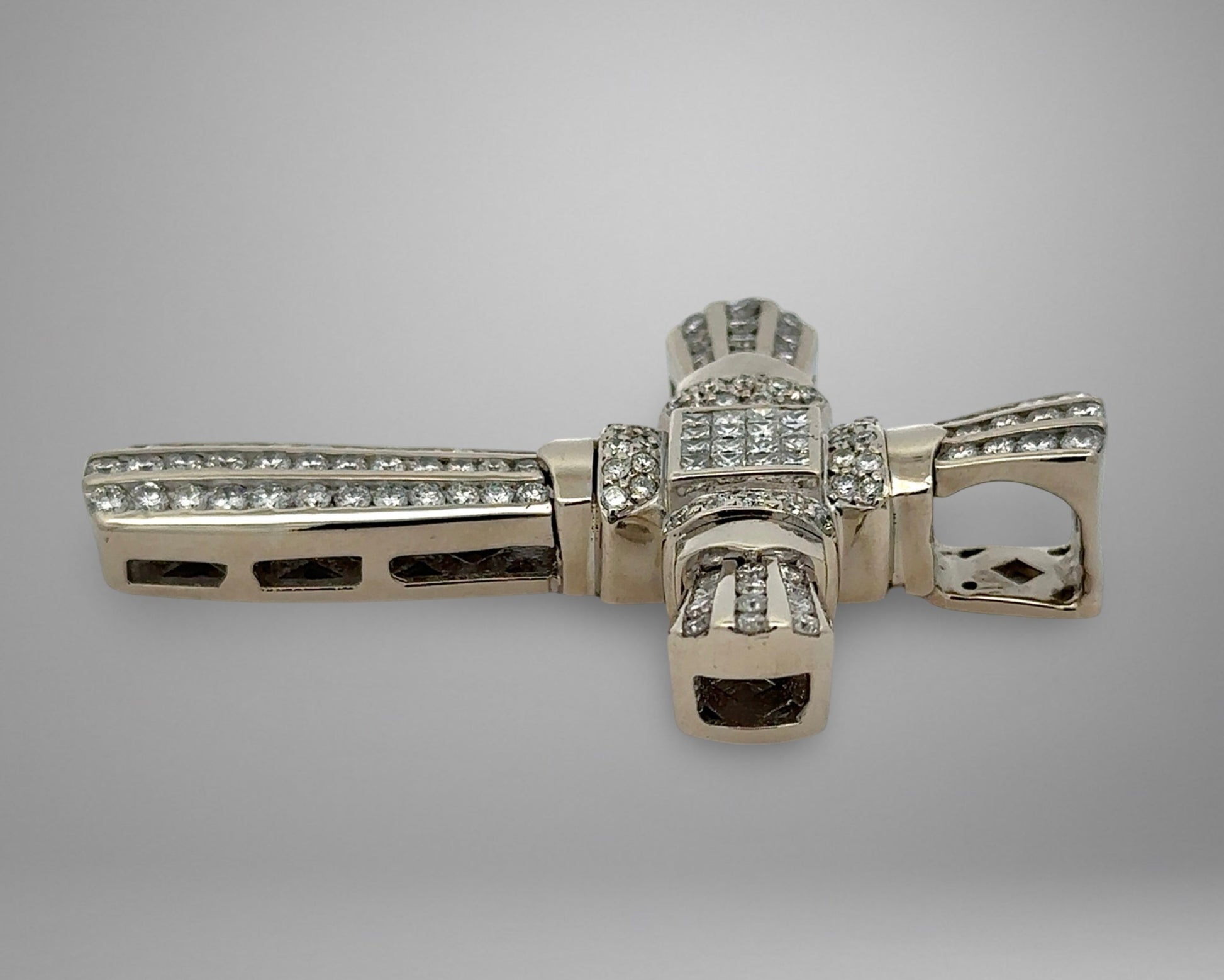 White gold diamond cross pendant on a gray background