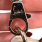 Close up of silver clasp on detachable strap with "Louboutin" signature