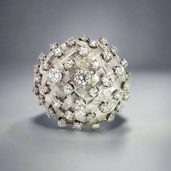 360 video of white gold dome-shaped diamond ring with diamonds in different sizes scattered on top and scratches on the band.