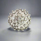 360 video of white gold dome-shaped diamond ring with diamonds in different sizes scattered on top and scratches on the band.